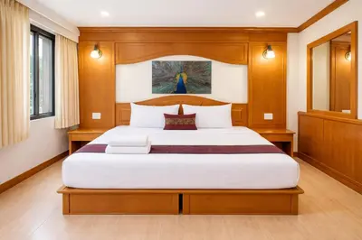 a bedroom with a large white bed with wood paneling at Tiger Complex Suites in Patong Beach