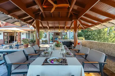 a dining room with tables and chairs on a patio at Arun Rapee Villa Surin Beach in Surin Beach