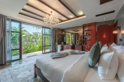 a bedroom with a large bed and a chandelier at Arun Rapee Villa Surin Beach in Surin Beach
