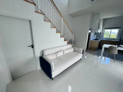 a living room with a couch and a staircase at Modern townhome in Phuket in Ban Phak Chit