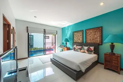 a bedroom with a bed and a blue wall at 3 BR Pool Villa Salika near Rawai Beach in Ban Saiyuan (1)