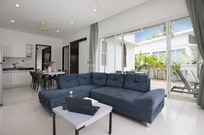a living room with a blue couch and a table at Green 9 Private Pool Villa 2BR near Rawai Beach in Ban Saiyuan (1)