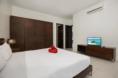 a bedroom with a large white bed and a flat screen tv at Green 9 Private Pool Villa 2BR near Rawai Beach in Ban Saiyuan (1)