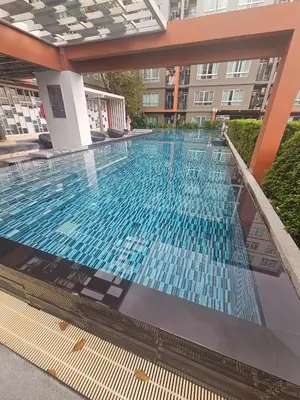 a swimming pool in a building with blue tiles at Dcondo in Ban Kathu