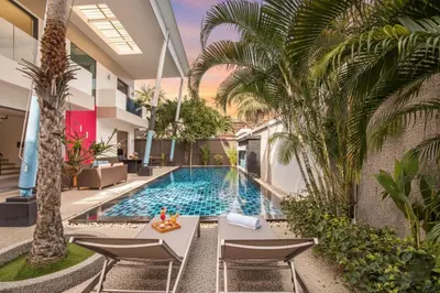 a pool in a building with chairs and palm trees at 3 BR Pool Villa Kloua near Chalong Temple in Ban Na Bon