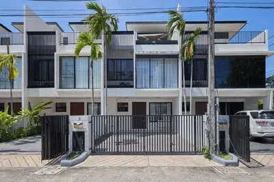 an apartment building with a gate and palm trees at Townhouse Laguna Park 3 bedrooms in Laguna Phuket
