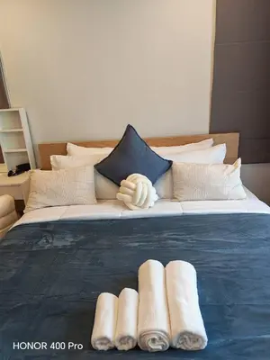 a bed with pillows and a blue comforter with four rolled towels at Phuket Paklok Cozy Home in Ban Pa Khlok