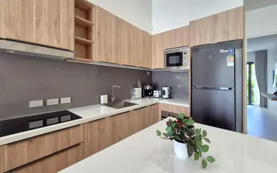 a kitchen with wooden cabinets and a black refrigerator at Luxury Private Christina Pool Villa in Ban Phak Chit