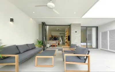 a living room with a blue couch and wooden chairs at Luxury Private Christina Pool Villa in Ban Phak Chit