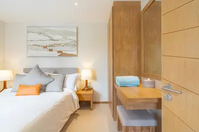 a bedroom with a bed and a wooden desk at The Sandstone Villa at Trichada Breeze in Laguna Phuket