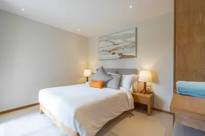 a bedroom with a white bed and two lamps at The Sandstone Villa at Trichada Breeze in Laguna Phuket