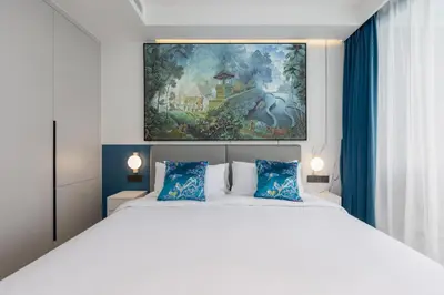 a bedroom with a white bed with a painting above it at Tinos 1BR Suite at Kora Beach Resort in Layan Beach