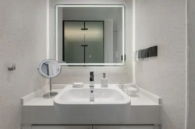 a bathroom with a white sink and a mirror at Tinos 1BR Suite at Kora Beach Resort in Layan Beach