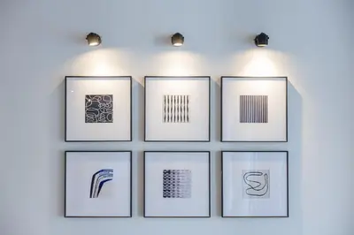a wall with four framed pictures on a wall with lights at PRAIA Residence 5BR - Bangtao in Ban Pak Lak