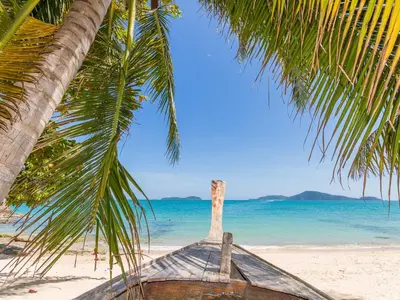 a boat sitting on the beach under a palm tree at Large 1 Bedroom Apt Sleeps 4, Close to Beach - RM 2 in Ban Lum Fuang