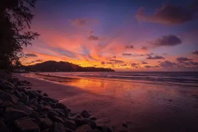 a sunset on a beach with rocks and the ocean at Large 1 Bedroom Apt, Sleeps 4, close to beach - RM 4 in Ban Lum Fuang