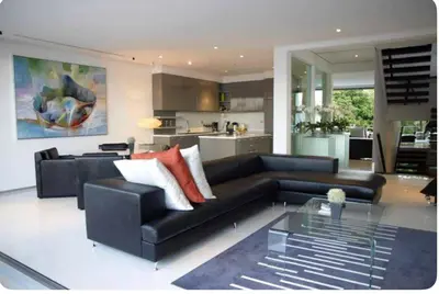 a living room with a black couch and a kitchen at Atika Villa 6 ocean view pool villa in Patong Beach