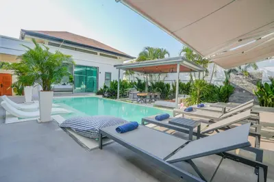 a swimming pool with lounge chairs and a house at Villa Tropicana - Luxury 4 Bedroom Villa in Rawai Beach