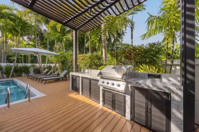 an outdoor kitchen with a grill and a swimming pool at Baan Bua Estate Villas by TropicLook in Nai Harn Beach