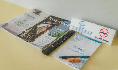 a book and a remote control sitting on a table at TheLifeCo Phuket - Holistic Wellbeing Center in Nai Thon Beach