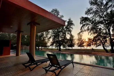 a couple of chairs sitting next to a swimming pool at Coriacea Beachfront Boutique Phuket Resort in Mai Khao Beach