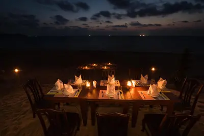 a table with candles on the beach at night at Coriacea Beachfront Boutique Phuket Resort in Mai Khao Beach