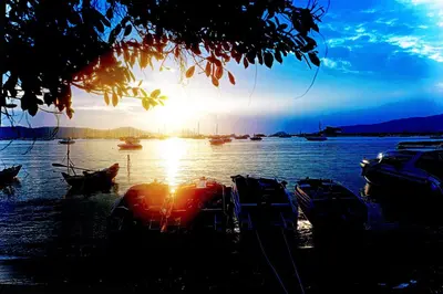 a group of boats docked on the water with the sunset at Phuket Paradiso in Chalong