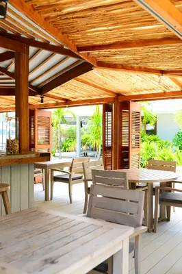 an outdoor patio with wooden tables and chairs at The Cove in Panwa Beach