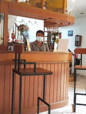 a man behind a bar wearing a mask at Ban Elephant Blanc Apartment in Kata Beach