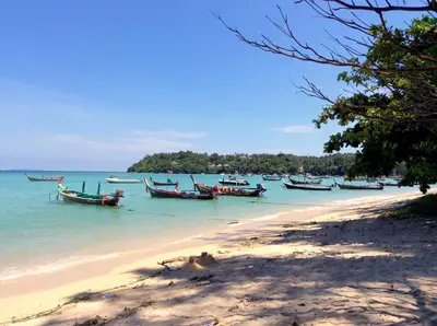 a group of boats in the water on a beach at Apartments in The Title Beach Rawai in Rawai Beach