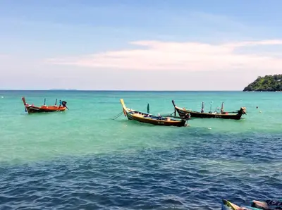 two boats sitting in the water in the ocean at Apartments in The Title Beach Rawai in Rawai Beach