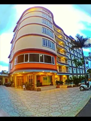 a large building on a street with a palm tree at Smile Residence in Rawai Beach