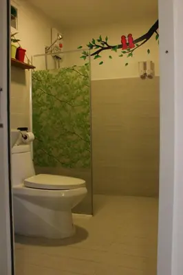 a bathroom with a toilet with a flower on the wall at 1715 House - White Rhino in Rawai Beach