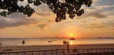 a sunset on a beach with boats in the water at Anyavee Krabi Beach Resort in Klong Muang Beach