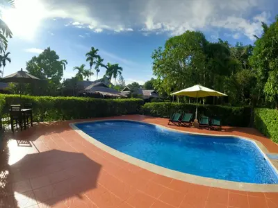 a swimming pool with two chairs and an umbrella at Cozy Garden Resort in Ao Nang Beach