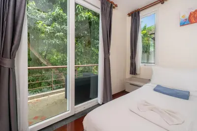 a bedroom with a bed and a large window at Baan Kaja Villa by Lofty in Surin Beach