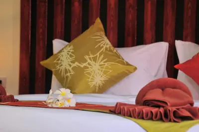 a bed with a yellow pillow and towels on it at Phi Phi Little Star Resort in Phi Phi Don