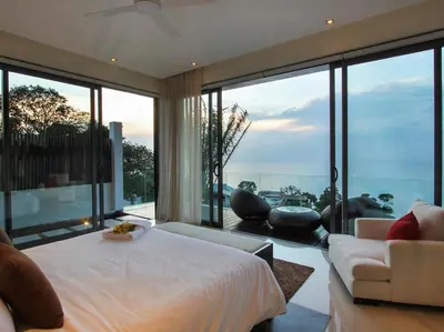 a bedroom with a bed and a couch and windows at Villa Saan - SHA Extra Plus in Kamala Beach