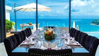 a table with chairs and a table with a view of the ocean at Villa Paradiso in Nai Thon Beach