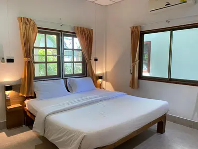a bedroom with a large white bed with windows at Coconut Bungalow in Nai Yang Beach