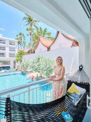 a woman standing on a balcony next to a swimming pool at Lub d Phuket Patong - Near Patong Beach & Vibrant Social Vibe in Patong Beach