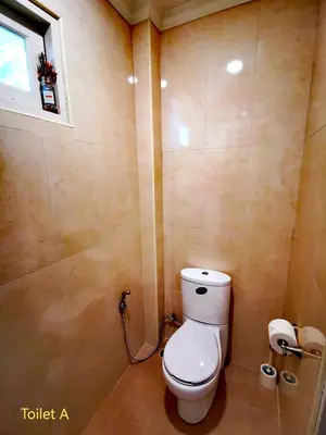 a bathroom with a toilet and a window at Vacation Garden Villa in Thalang
