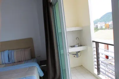 a bedroom with a bed and a window with a sink at The C Park in Patong Beach