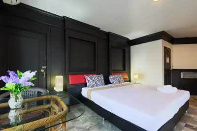 a bedroom with two beds and a glass table at Patong Holiday Dream Hotel in Patong Beach