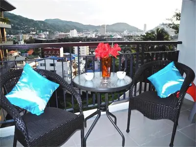 a table with two chairs and a vase with flowers on a balcony at Bliss Patong 2 bedrooms Apartment in Patong Beach