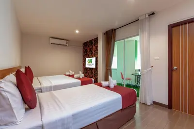 a hotel room with two beds and a table at Tee Pak Dee Resident Phuket in Phuket Town