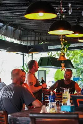 a group of men sitting at a bar at Naiharn Beach Resort - SHA Plus Extra in Nai Harn Beach