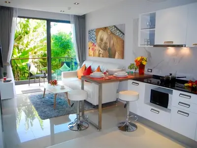 a kitchen with a couch and a table in a room at Emerald Patong 1 bedroom Apartment Garden View in Patong Beach