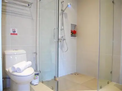 a bathroom with a glass shower with a toilet at Emerald Patong 1 bedroom Apartment Garden View in Patong Beach