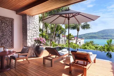 a wooden deck with chairs and an umbrella at Andara Resort Villas in Kamala Beach